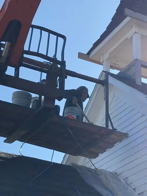 Workers restoring the side of a historic building.