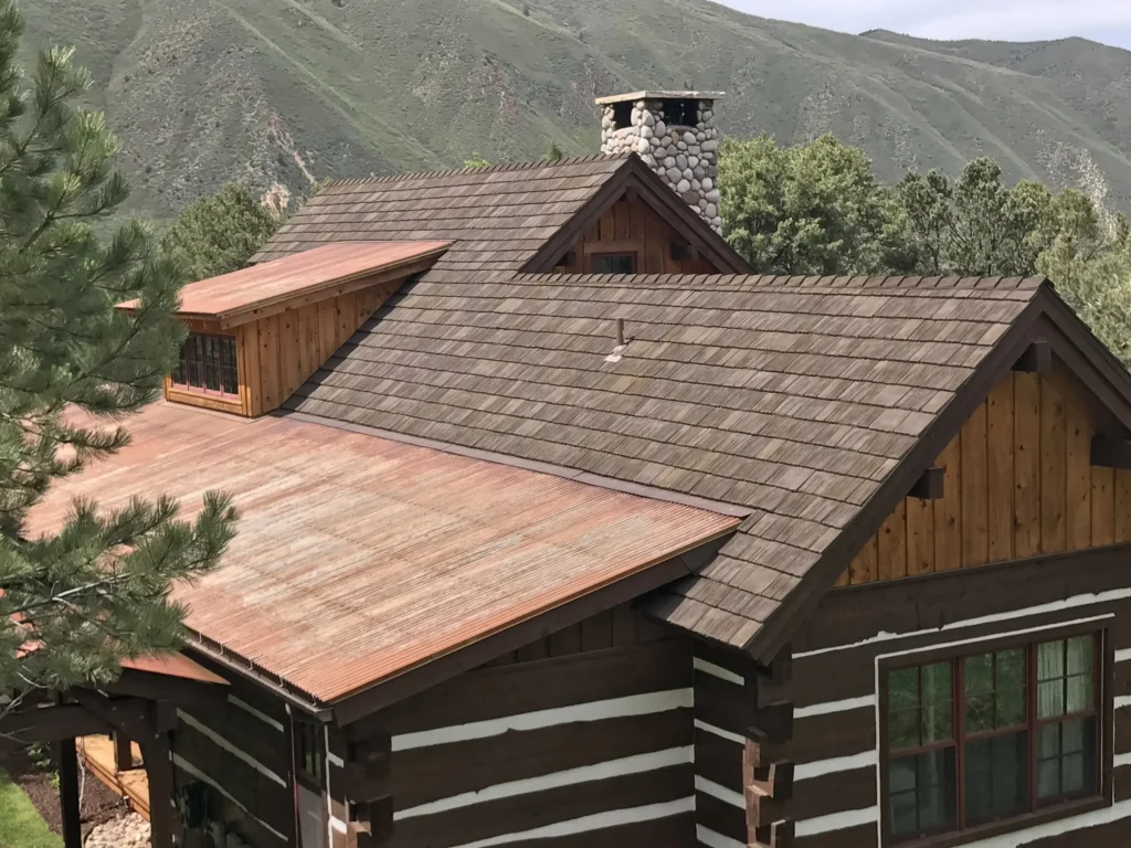 Rustic mountain cabin with synthetic cedar shake roof and stone chimney.