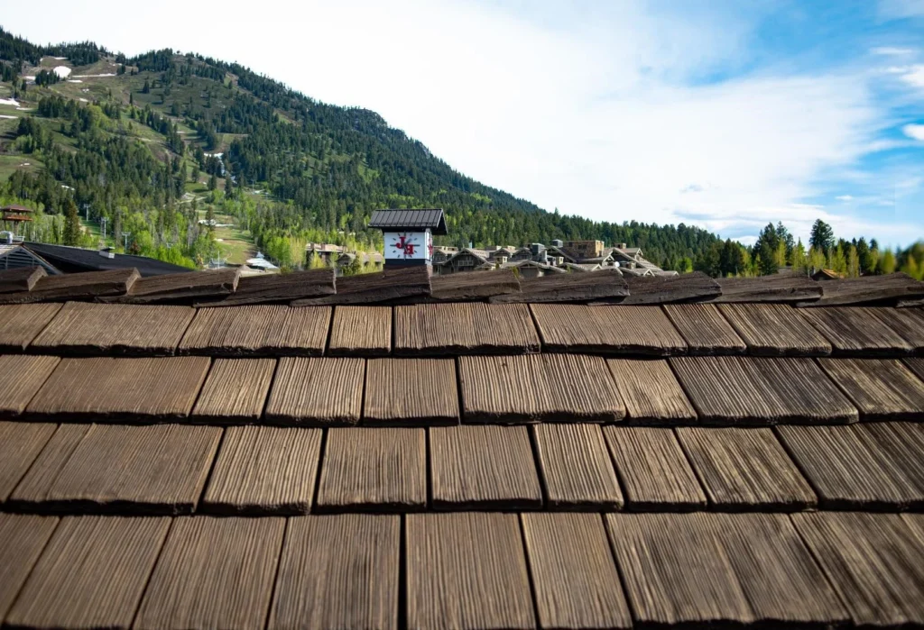 Wood shake roof installed on a mountain home with a scenic hillside backdrop.