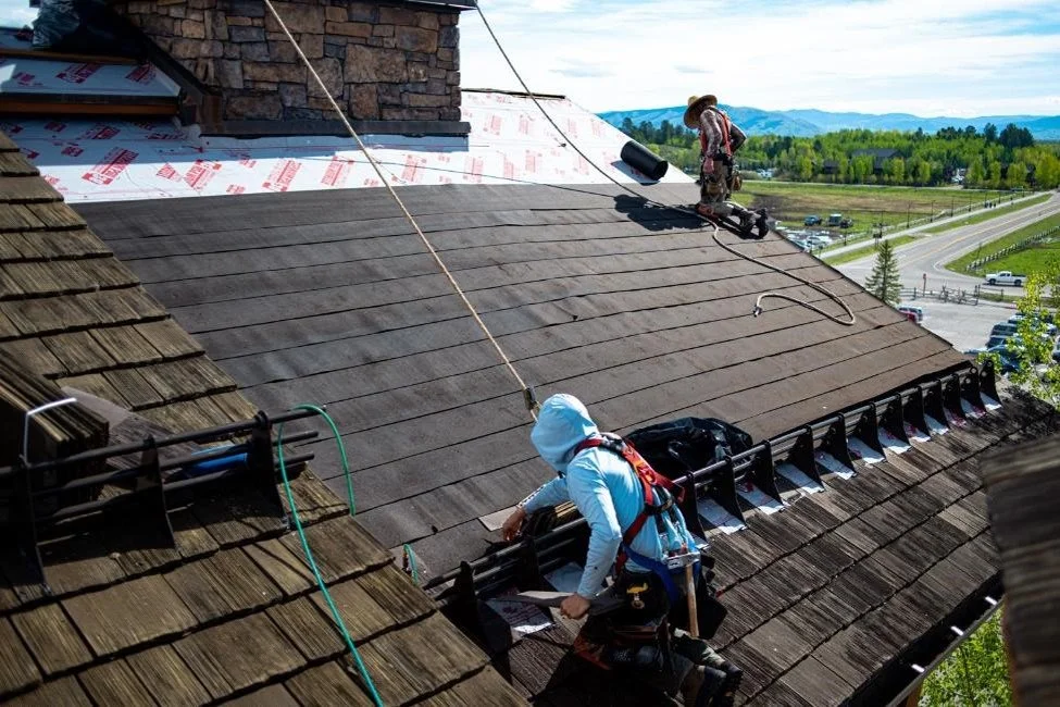 Roofer replacing synethic CEDUR roof shingles on a house.