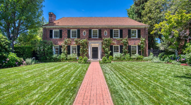 Brick colonial-style home with manicured lawn.