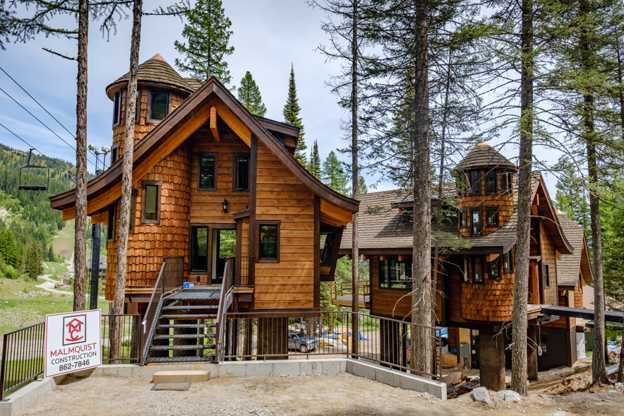 Mountain home featuring a CeDUR synthetic shingle roof surrounded by tall pine trees.