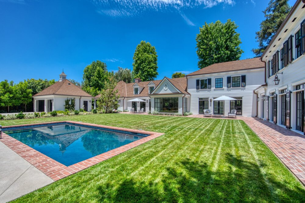 Large estate home with a CeDUR synthetic shingle roof overlooking a backyard pool and lawn.