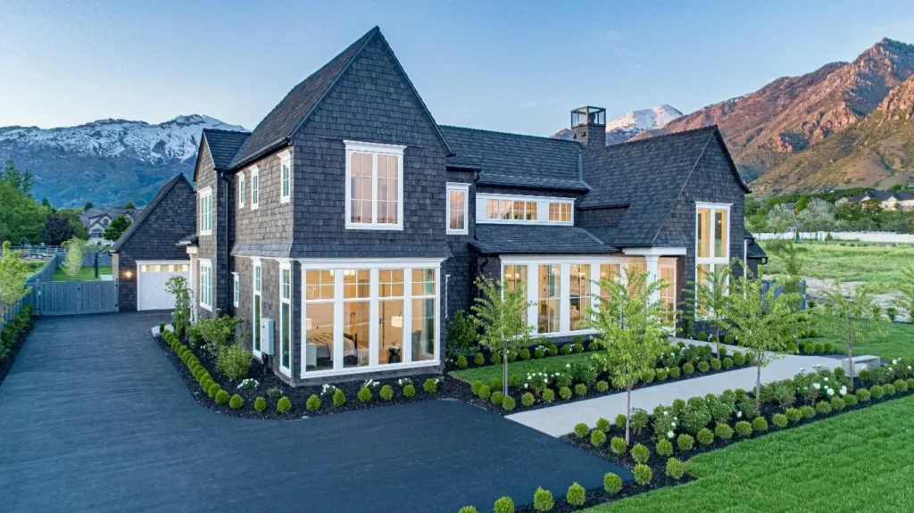 An image of a two-story house nestled in the mountains, topped with a rustic cedar shake roof.