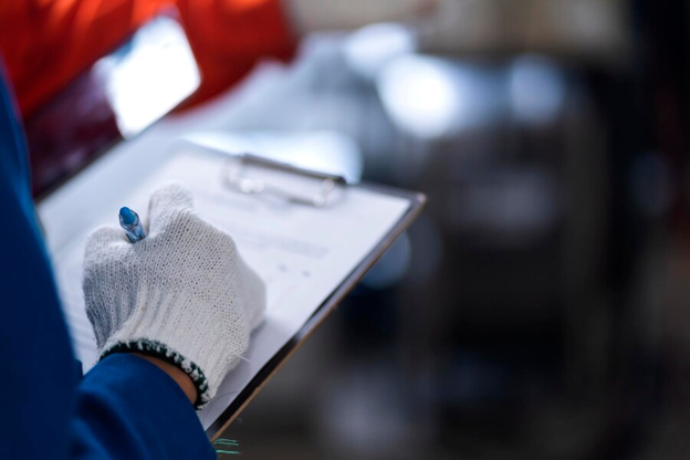 An image of a worker filling out paperwork on a clipboard.
