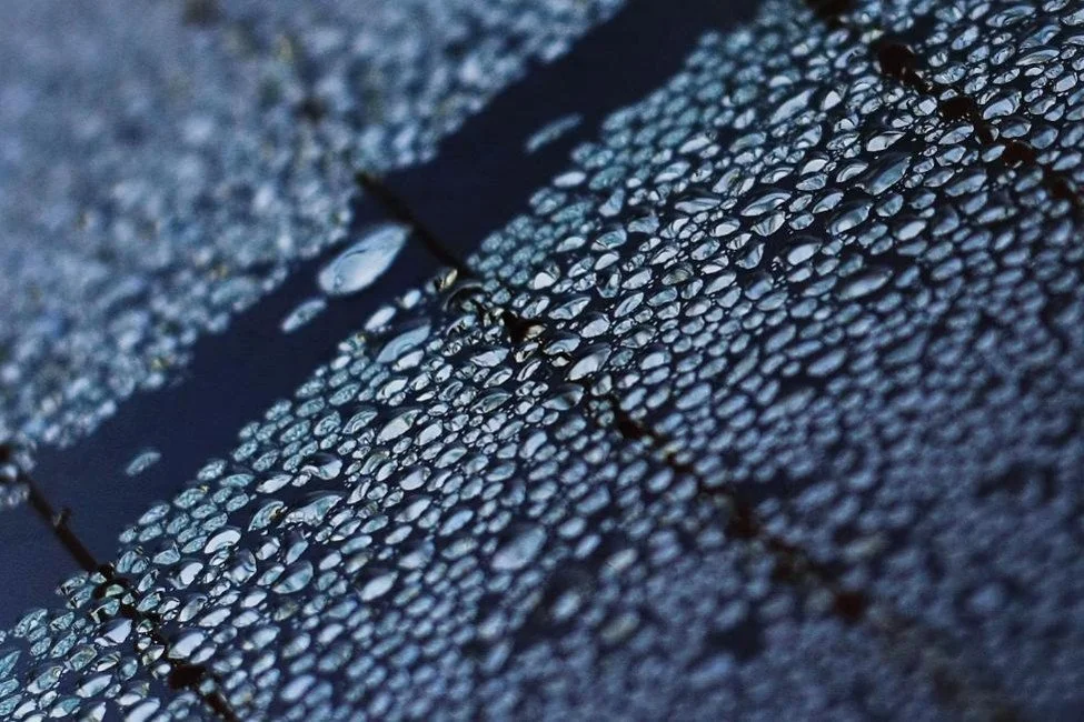Close-up of water droplets on a modified bitumen roof surface.