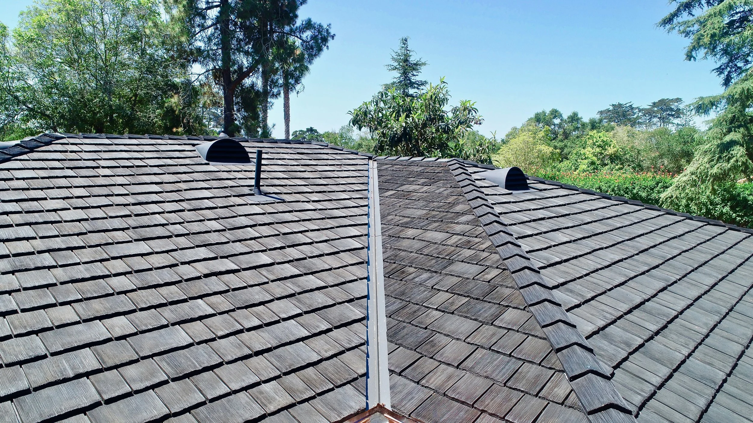 Close-up view of a synthetic shake roof surrounded by trees.