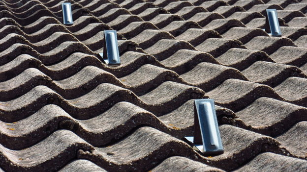 Close-up of aging concrete roof tiles with visible wear and raised vents.