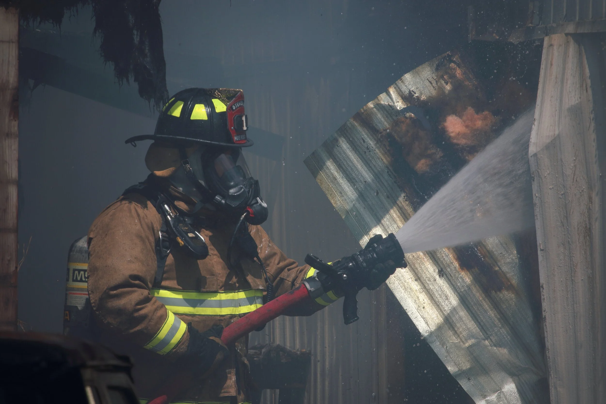 Firefighter putting out a home with fire inside.