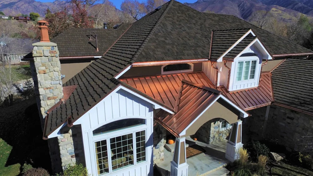 Luxury home with composite shake roofing and copper metal accents across multiple rooflines.